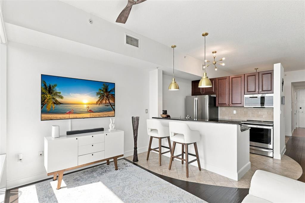 A modern kitchen with dark wood cabinets and a breakfast bar overlooks a living area — 101 S EOLA DRIVE UNIT 905, ORLANDO, FL