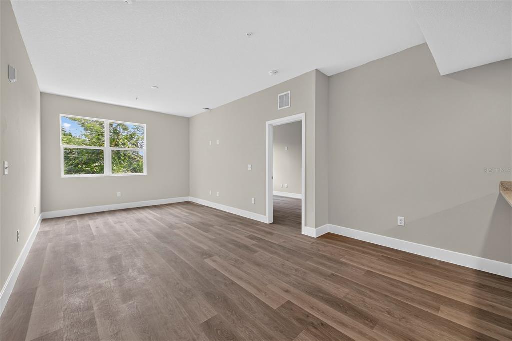 An empty room features light gray walls, dark wood-look flooring, and a doorway to another room — 4424 S TEXAS AVENUE UNIT 217, ORLANDO, FL