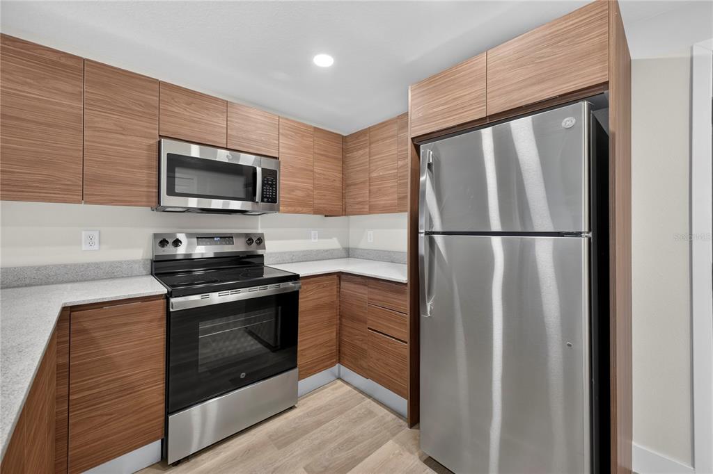 A kitchen features wood-grain cabinets, stainless steel appliances, and light-colored countertops — 4424 S TEXAS AVENUE UNIT 217, ORLANDO, FL