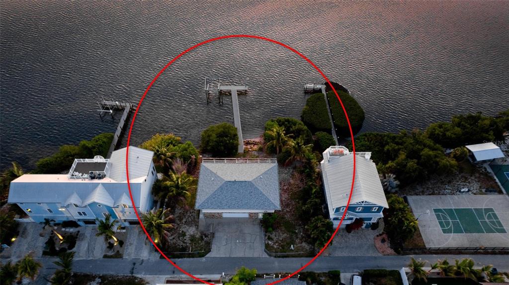 An aerial view shows a waterfront house with a private dock and a gray roof — 2512 AVENUE A, BRADENTON BEACH, FL