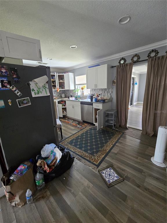 A kitchen features white cabinets, stainless steel appliances, wood-look flooring, and a patterned area rug — 125 EDGEWATER DRIVE, WINTER HAVEN, FL