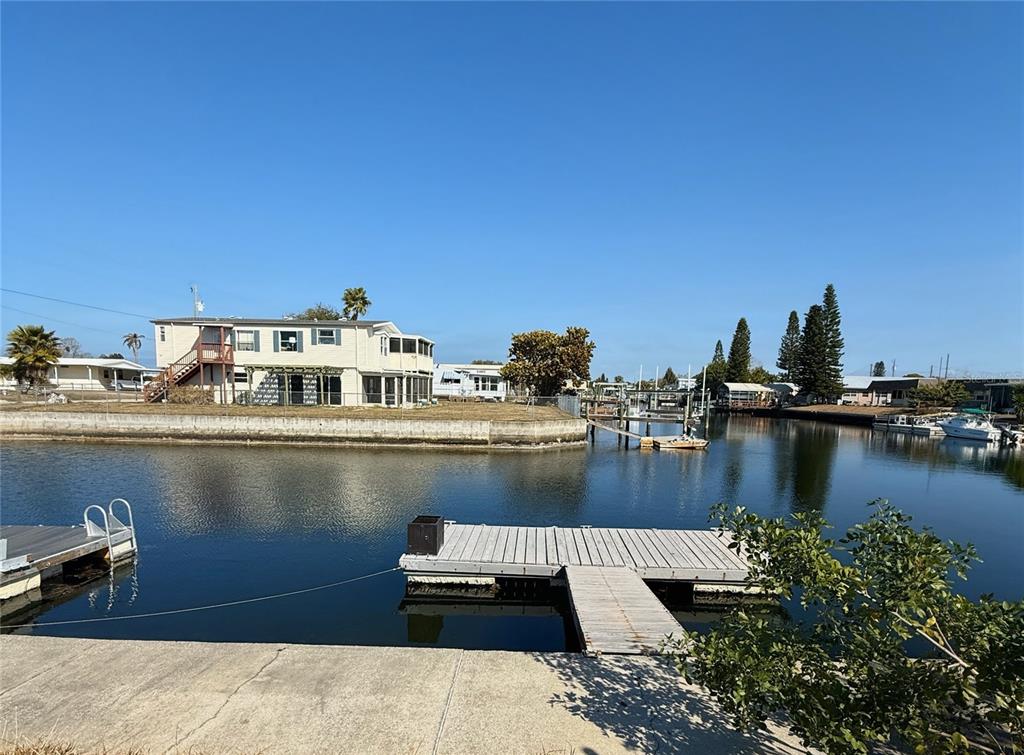 A view of a canal with a wooden dock in the foreground and houses beyond — 6411 TOWER DRIVE, HUDSON, FL