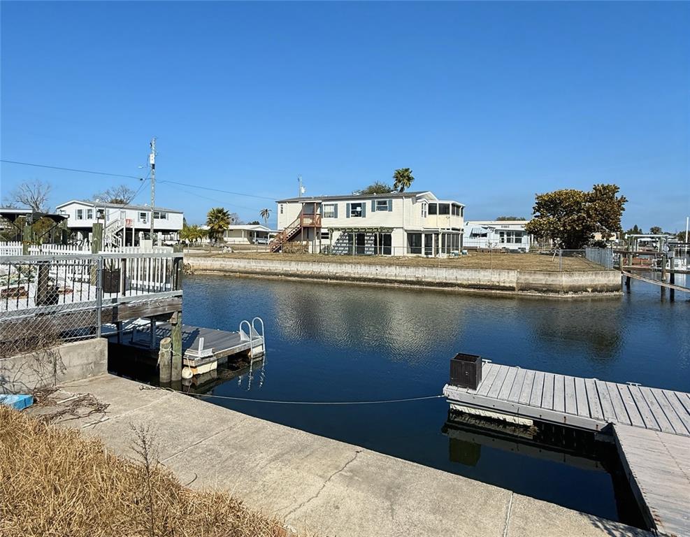 A canal-front property features a two-story house, a wooden dock, and a concrete bulkhead — 6411 TOWER DRIVE, HUDSON, FL
