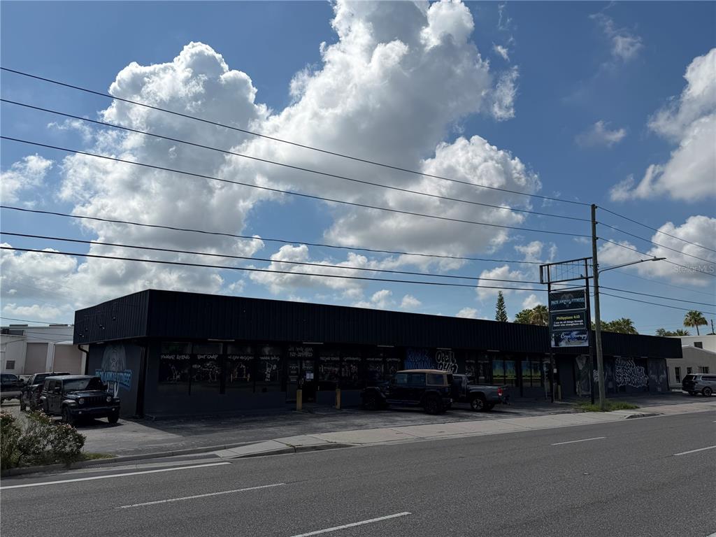A low-rise commercial building with a black facade and parking lot under a cloudy sky — 5983 49TH STREET N, ST PETERSBURG, FL