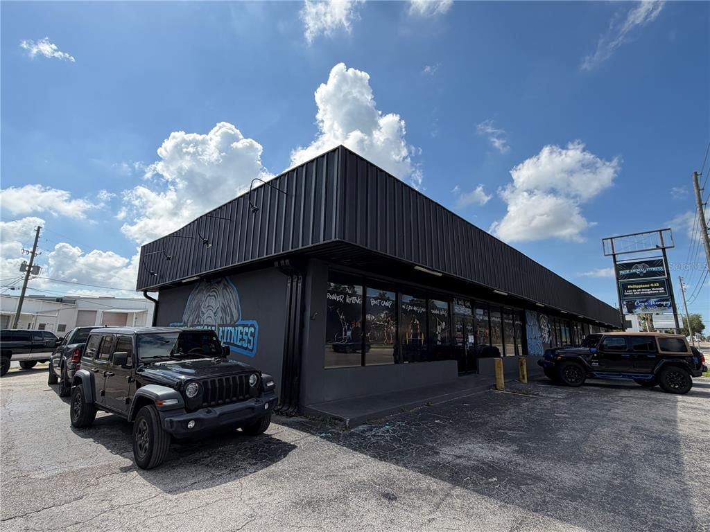 A black-painted commercial building with a fitness center logo and parked Jeeps outside — 5983 49TH STREET N, ST PETERSBURG, FL