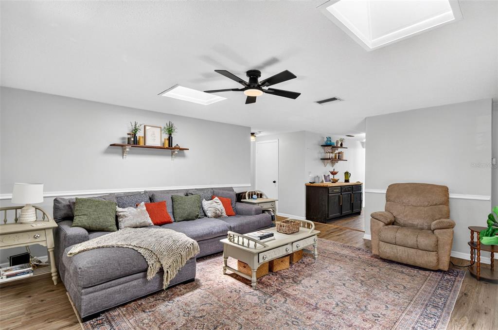 A living room features a gray sectional sofa, a recliner, and a coffee table on flooring — 7235 ASTOR DRIVE, NEW PORT RICHEY, FL