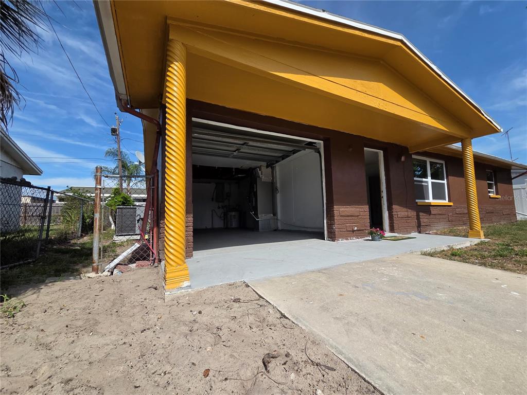 A house exterior features a brown brick facade, a covered carport, and yellow spiral columns — 4645 IRENE LOOP, NEW PORT RICHEY, FL