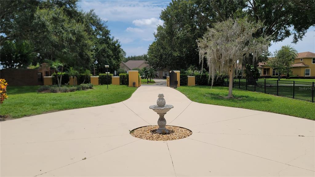 A concrete driveway leads through a gated entrance toward a house with a central fountain — 13503 LAKE CAWOOD DRIVE, WINDERMERE, FL