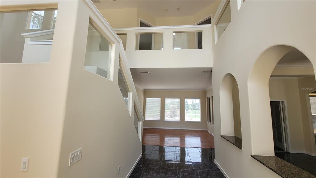 An interior view of a foyer with a staircase, glass railings, and tile flooring — 13503 LAKE CAWOOD DRIVE, WINDERMERE, FL