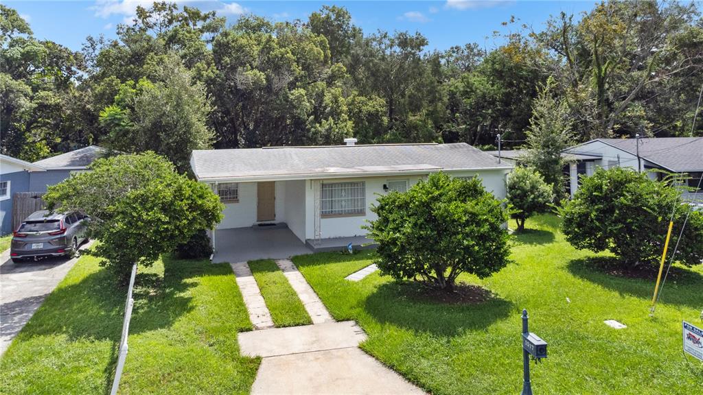 A single-story white house with a carport, concrete driveway, and security bars on the windows — 1517 RILEY AVENUE, ORLANDO, FL