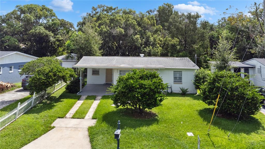 A single-story white house with a concrete driveway and a front lawn under a cloudy sky — 1517 RILEY AVENUE, ORLANDO, FL