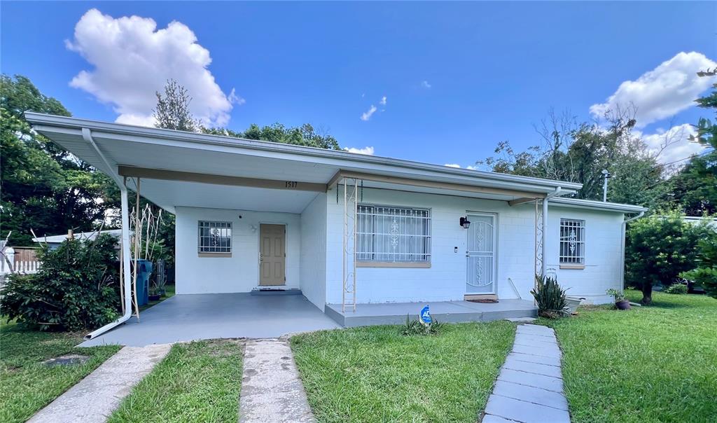 A single-story white house with a carport, a concrete driveway, and a front lawn — 1517 RILEY AVENUE, ORLANDO, FL