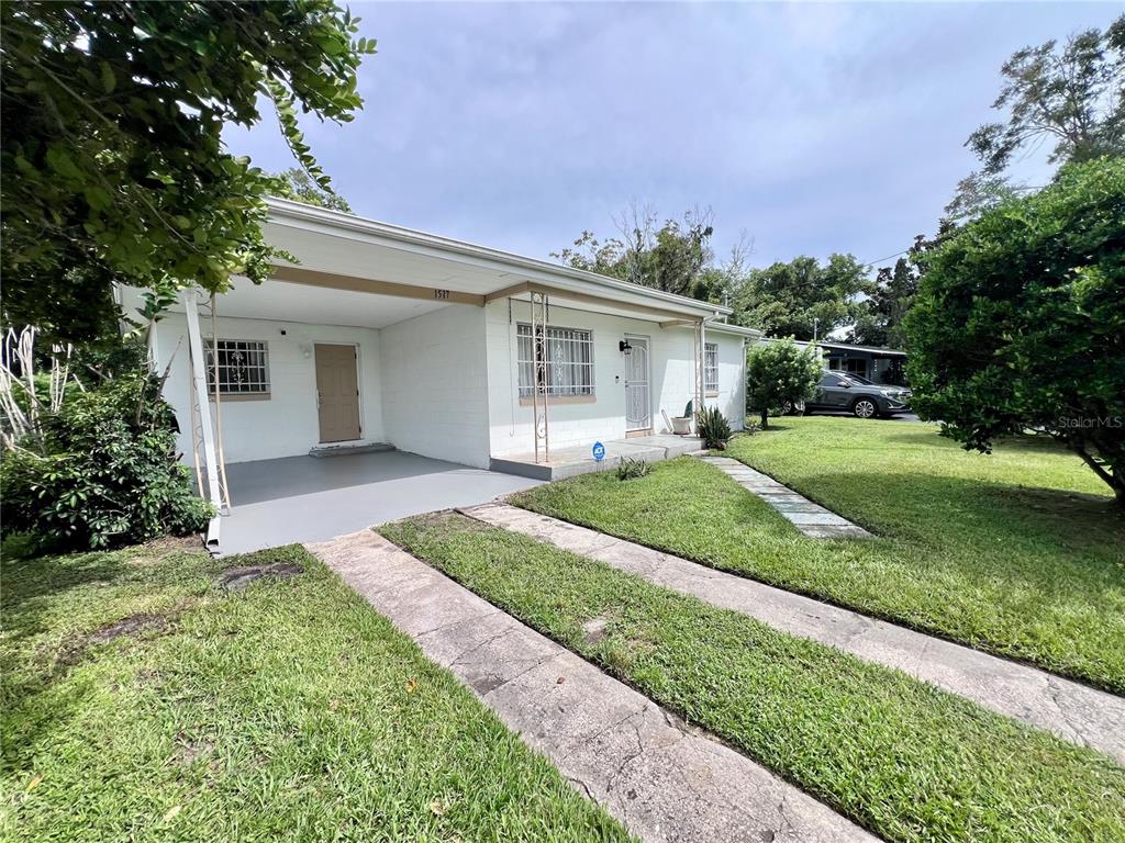 A white house with a concrete walkway and a green lawn under a cloudy sky — 1517 RILEY AVENUE, ORLANDO, FL