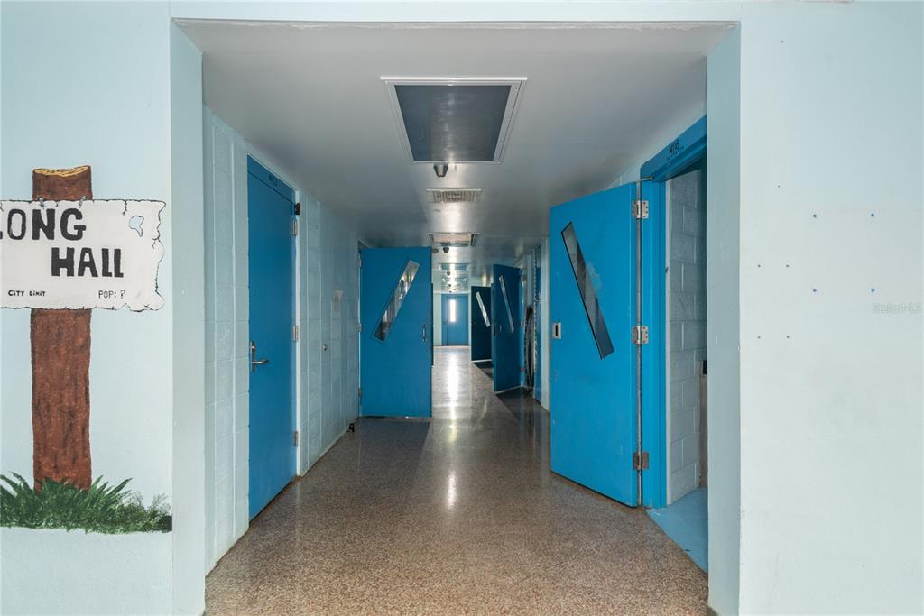 A hallway with light blue walls, a speckled floor, and several bright blue doors — 5871 SE HIGHWAY 31 UNIT 12, ARCADIA, FL