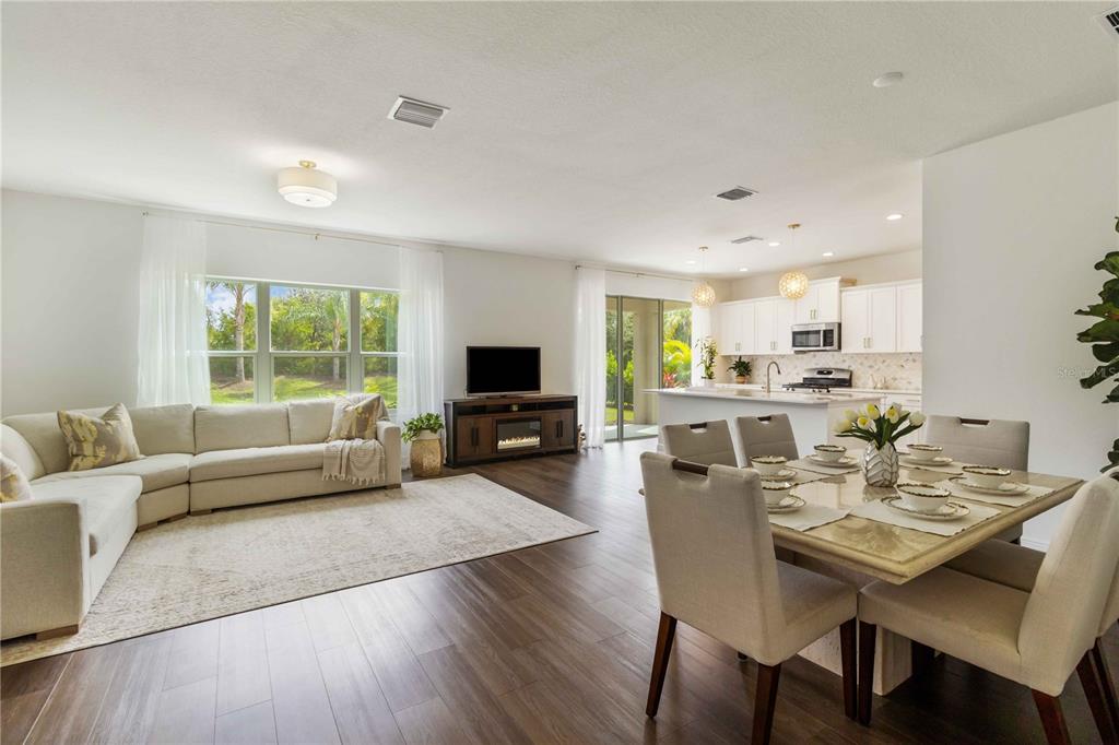 An open-concept living and dining area features a sectional sofa, television console, and kitchen island — 10109 CANAVERAL CIRCLE, SARASOTA, FL