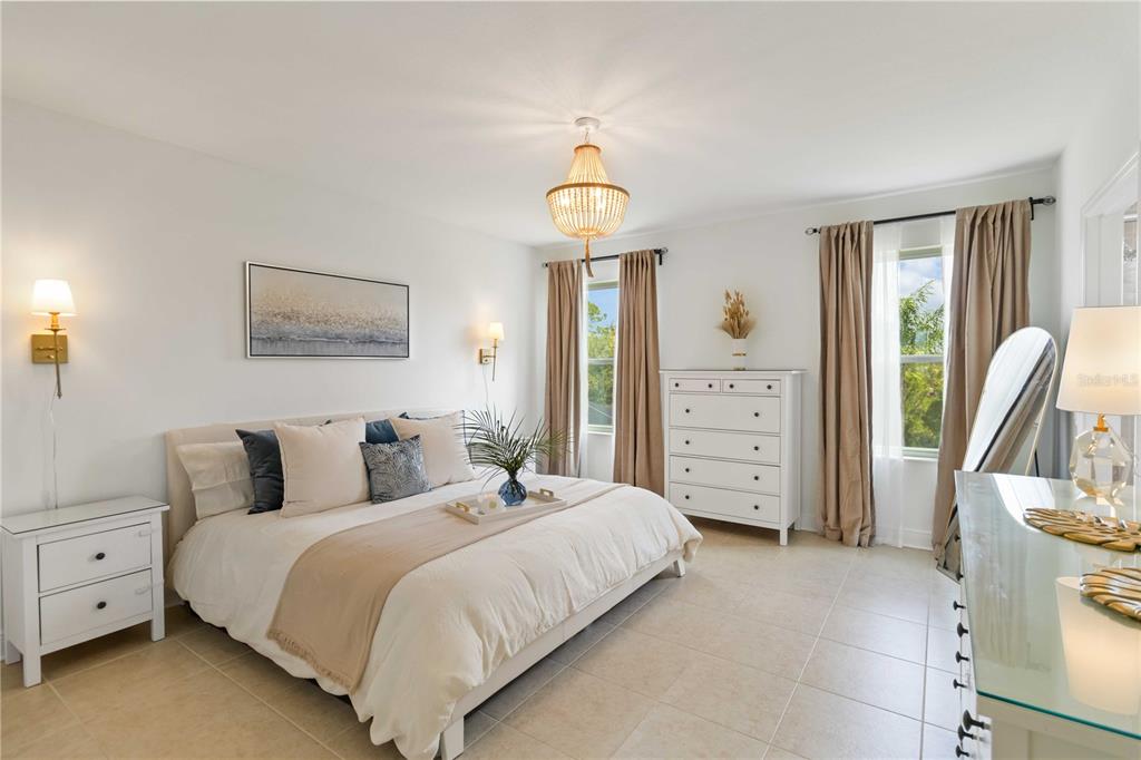 A bedroom features a bed, white dresser, chandelier, and two windows with tan curtains — 10109 CANAVERAL CIRCLE, SARASOTA, FL