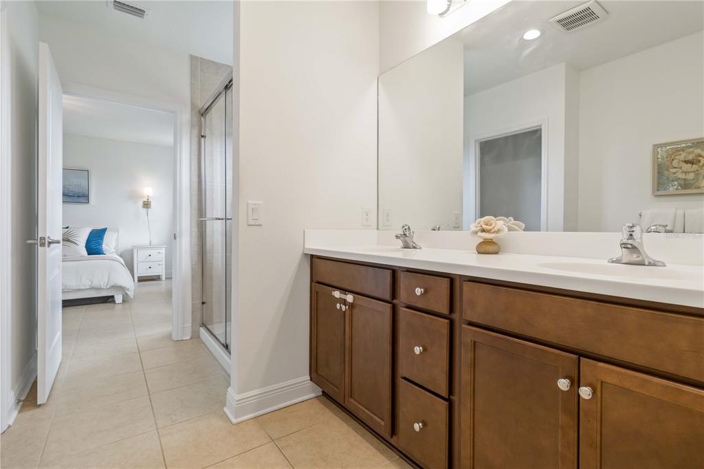 A bathroom features a double vanity with dark wood cabinets, a large mirror, and a shower — 10109 CANAVERAL CIRCLE, SARASOTA, FL
