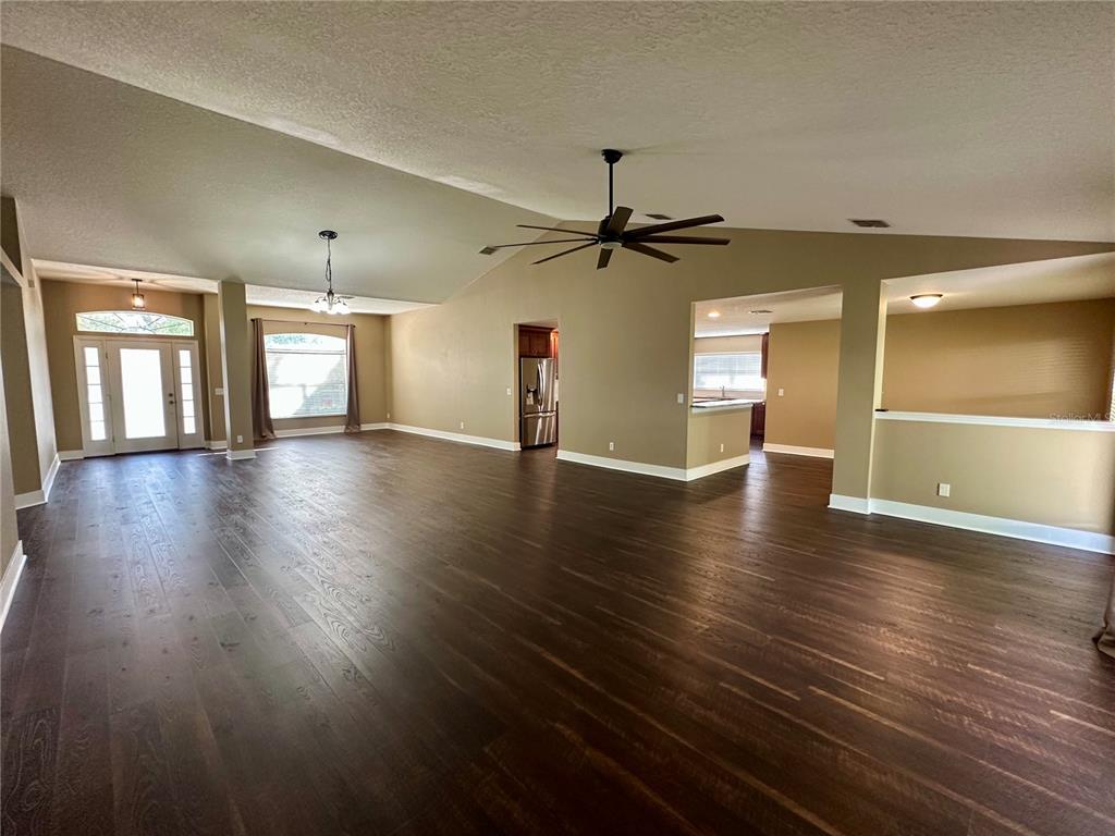 A spacious living area with vaulted ceilings, hardwood floors, and an open kitchen view — 531 HEARTHGLEN BOULEVARD, WINTER GARDEN, FL