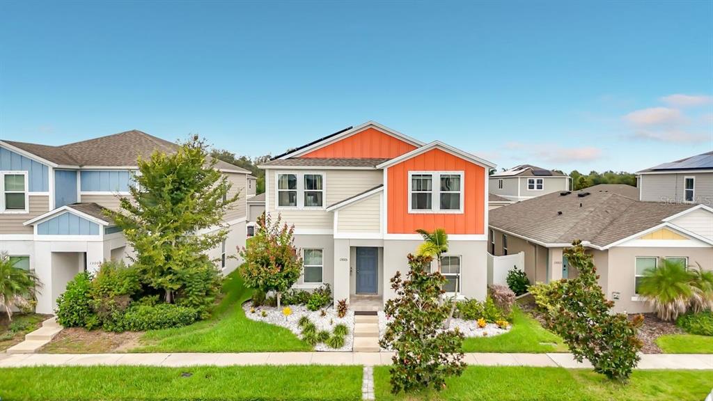 A two-story suburban house with orange and beige siding, a front yard, and landscaping — 13005 UPWARD PLACE, RIVERVIEW, FL