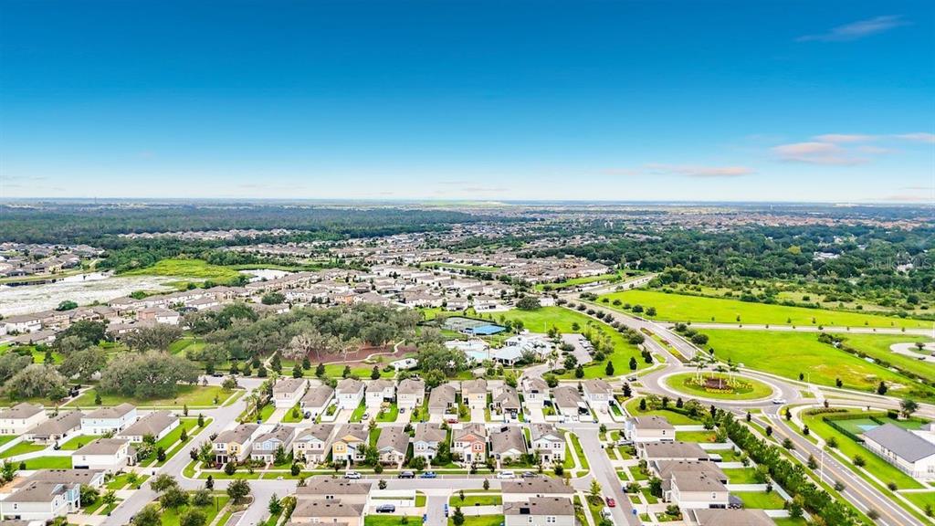 Aerial view of a suburban residential neighborhood featuring houses, a roundabout, and surrounding green space — 13005 UPWARD PLACE, RIVERVIEW, FL