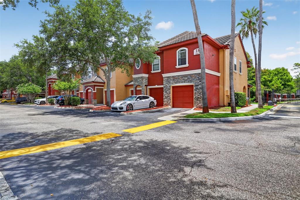 A red front door with a lockbox sits under an arched entryway with orange stucco — 2217 TUSCANY TRACE UNIT 7, PALM HARBOR, FL