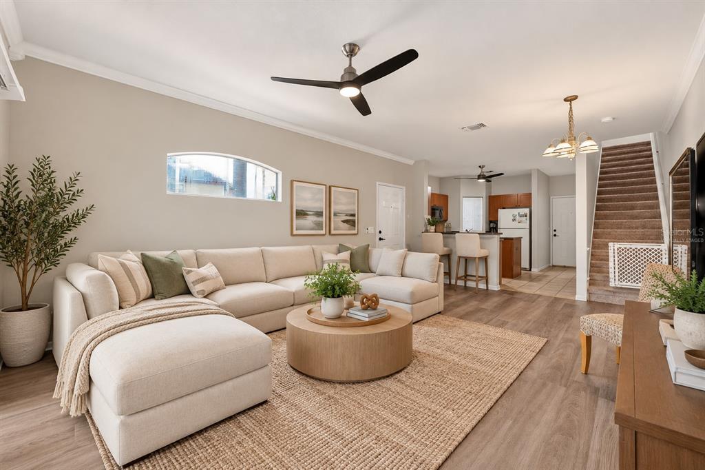 A living room features a grey sectional sofa, wood-look flooring, a ceiling fan, and sliding doors — 2217 TUSCANY TRACE UNIT 7, PALM HARBOR, FL
