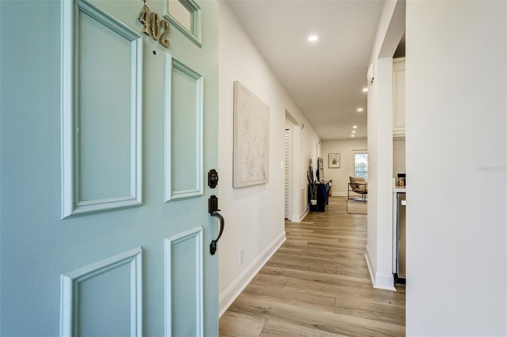 A view through an open light blue door into a hallway with wood-look flooring — 460 S PAULA DRIVE UNIT 402, DUNEDIN, FL
