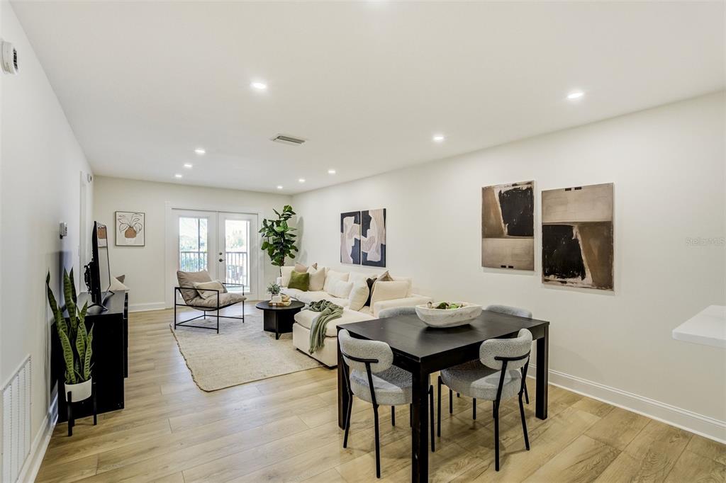 A living and dining area with light wood floors, white walls, and modern furniture — 460 S PAULA DRIVE UNIT 402, DUNEDIN, FL
