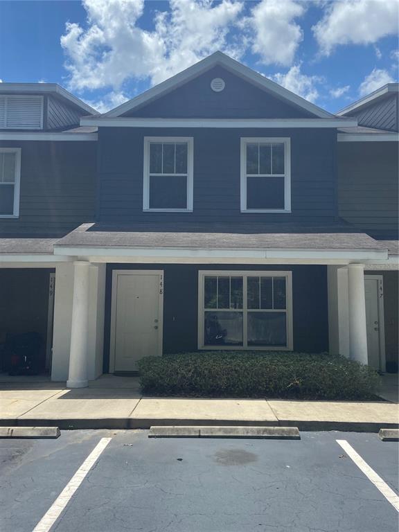 A two-story townhouse exterior features dark blue siding, a covered porch, and a parking space — 2348 SW 42ND DRIVE UNIT 148, GAINESVILLE, FL