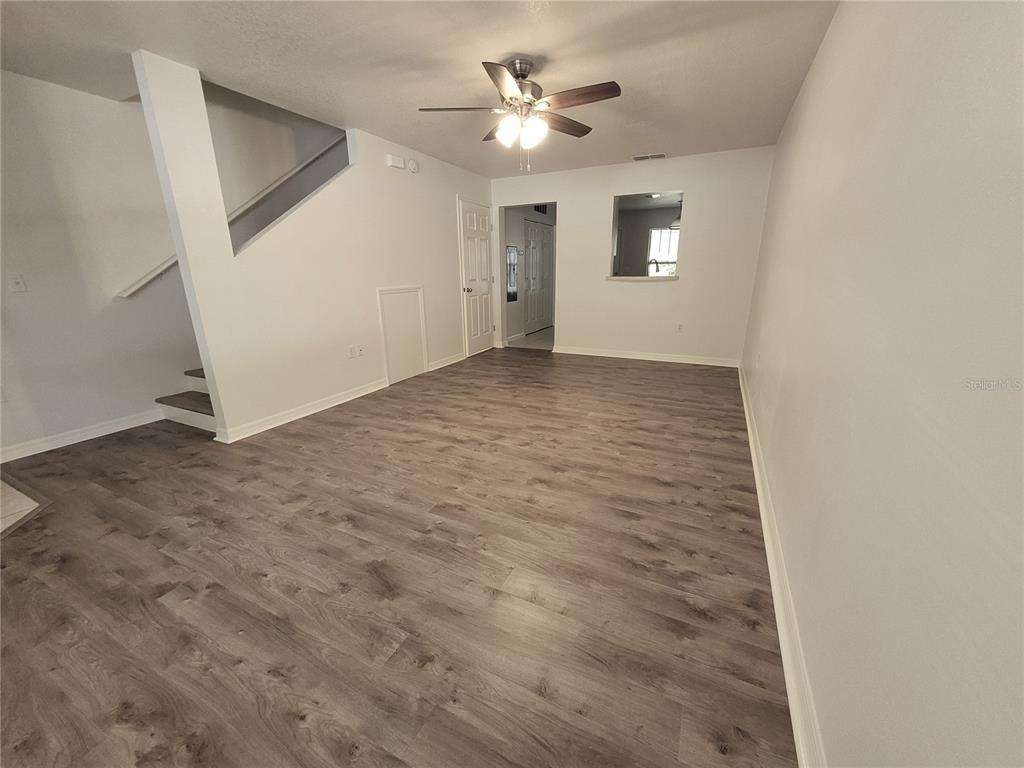 An empty living room features gray wood-look flooring, white walls, and a ceiling fan — 2348 SW 42ND DRIVE UNIT 148, GAINESVILLE, FL