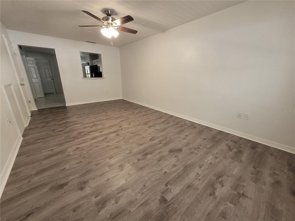 An empty room features gray wood-look flooring, white walls, and a ceiling fan — 2348 SW 42ND DRIVE UNIT 148, GAINESVILLE, FL
