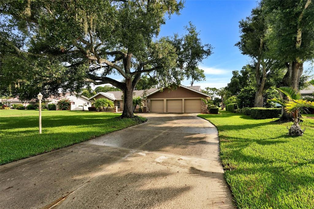 A concrete driveway leads to a three-car garage in front of a single-story suburban house — 7913 BROADMOOR PINES BOULEVARD, SARASOTA, FL