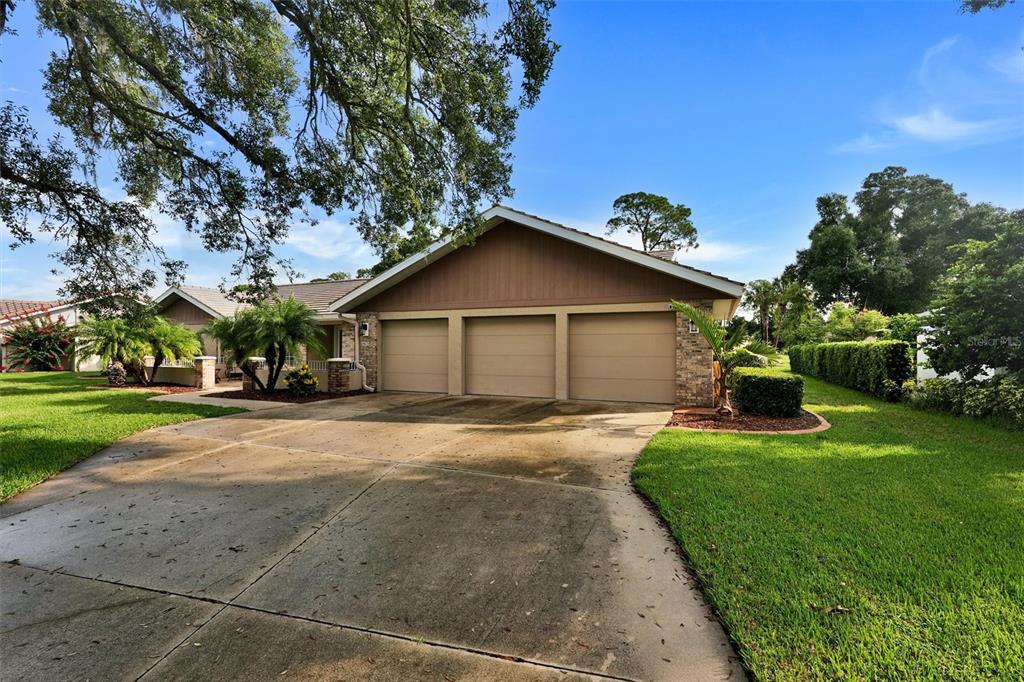 A three-car garage with a concrete driveway sits in front of a single-story suburban house — 7913 BROADMOOR PINES BOULEVARD, SARASOTA, FL