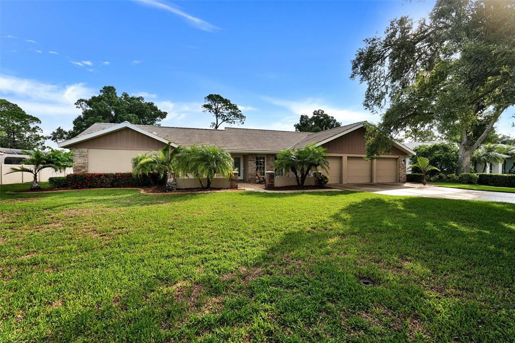 A single-story house with a three-car garage, palm trees, and a large front lawn — 7913 BROADMOOR PINES BOULEVARD, SARASOTA, FL