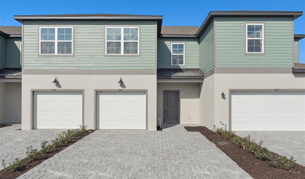 A multi-unit residential building exterior featuring white garage doors, light green siding, and paved driveways — 2278 RED PINE COURT, EUSTIS, FL