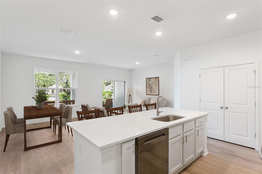 A kitchen island with a stainless steel dishwasher faces a dining area and living room — 2278 RED PINE COURT, EUSTIS, FL
