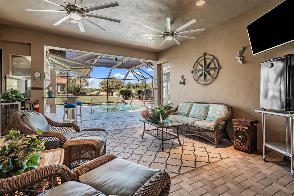A covered patio features wicker furniture, ceiling fans, a patterned rug, and a pool view — 34115 AMERICANA AVENUE, DADE CITY, FL