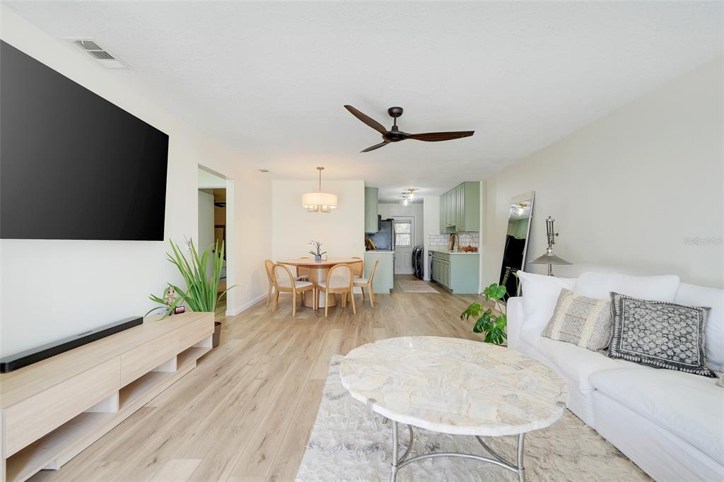 A bright open-concept living and dining area features light wood flooring and sage green kitchen cabinets — 30024 TAVARES RIDGE BOULEVARD UNIT 62, TAVARES, FL