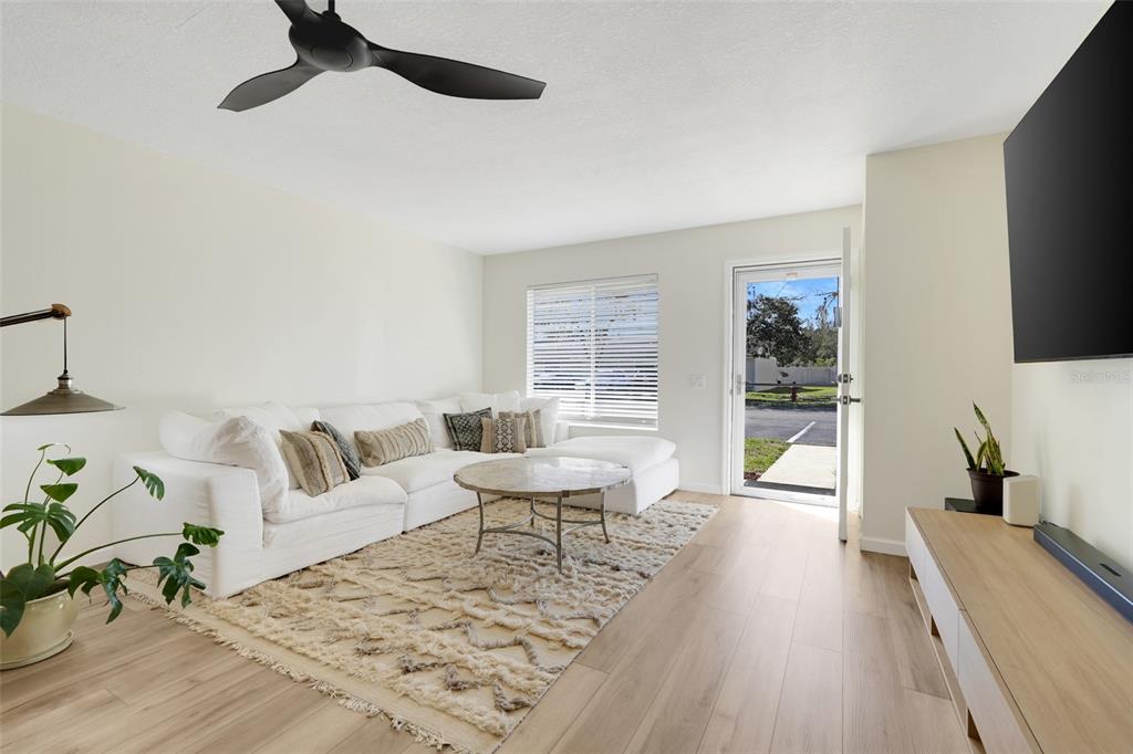 A living room features a white sectional sofa, a textured rug, and light wood flooring — 30024 TAVARES RIDGE BOULEVARD UNIT 62, TAVARES, FL