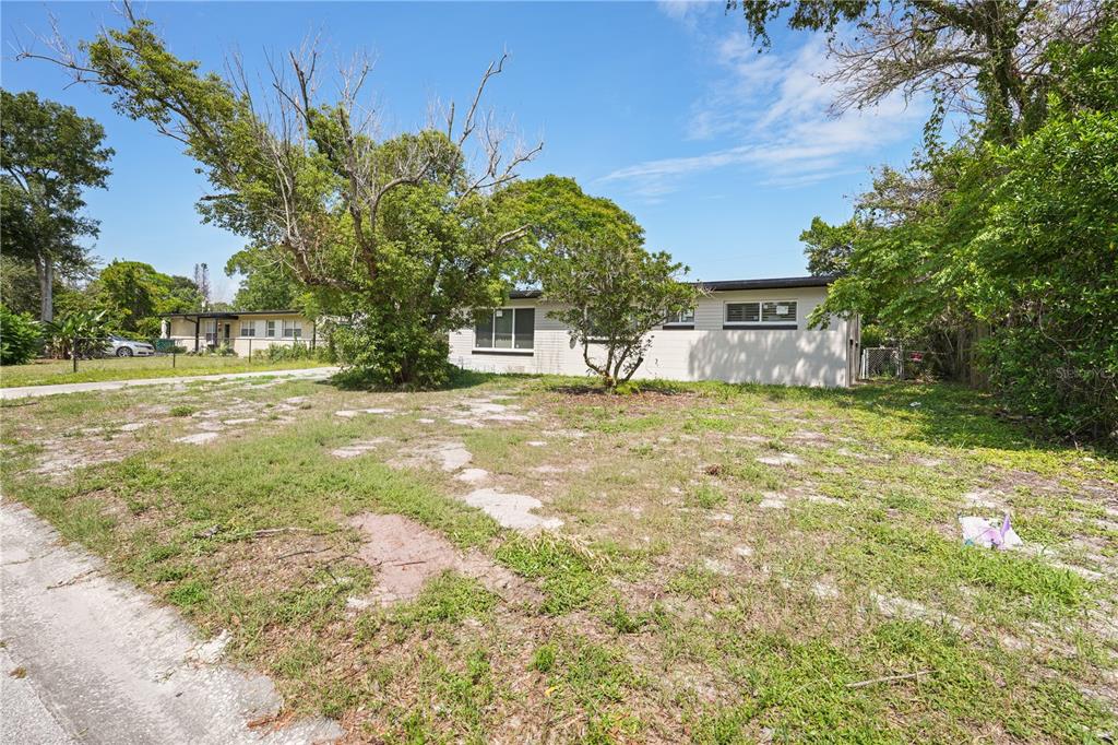 A single-story house with a light-colored exterior sits behind a large, grassy, unpaved front yard — 1506 HARVARD DRIVE, COCOA, FL