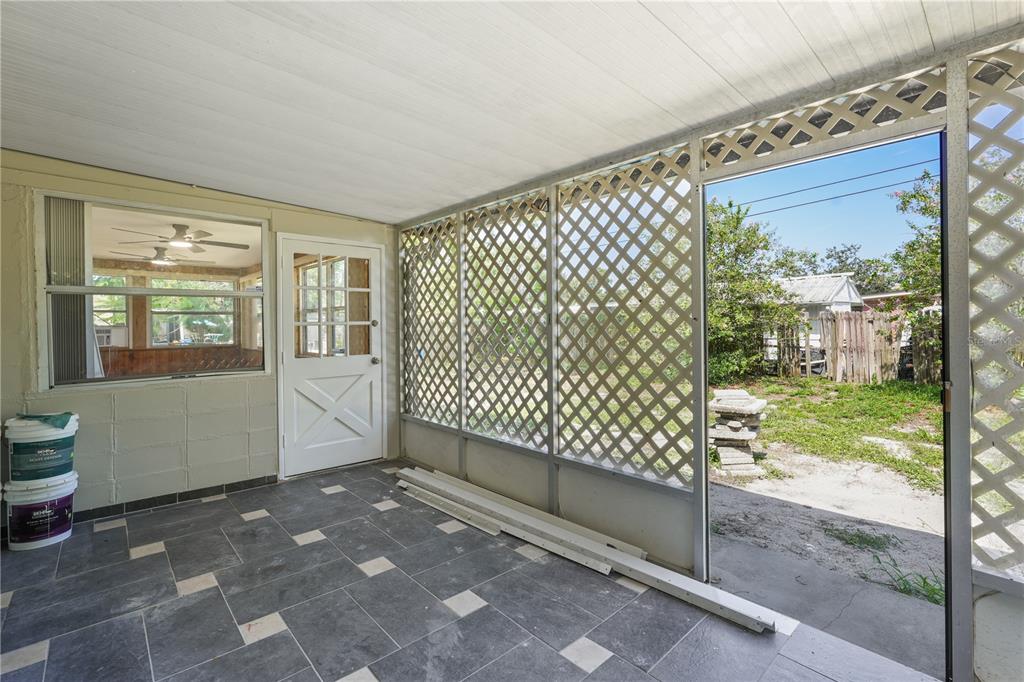 A covered patio with tiled flooring, lattice walls, and a door leading to a backyard — 1506 HARVARD DRIVE, COCOA, FL