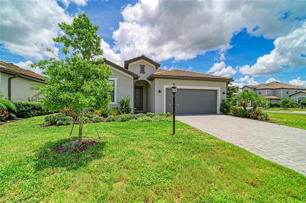 A single-story suburban house with a gray exterior, tiled roof, and a paved driveway — 15045 SERENE SHORES LOOP, BRADENTON, FL
