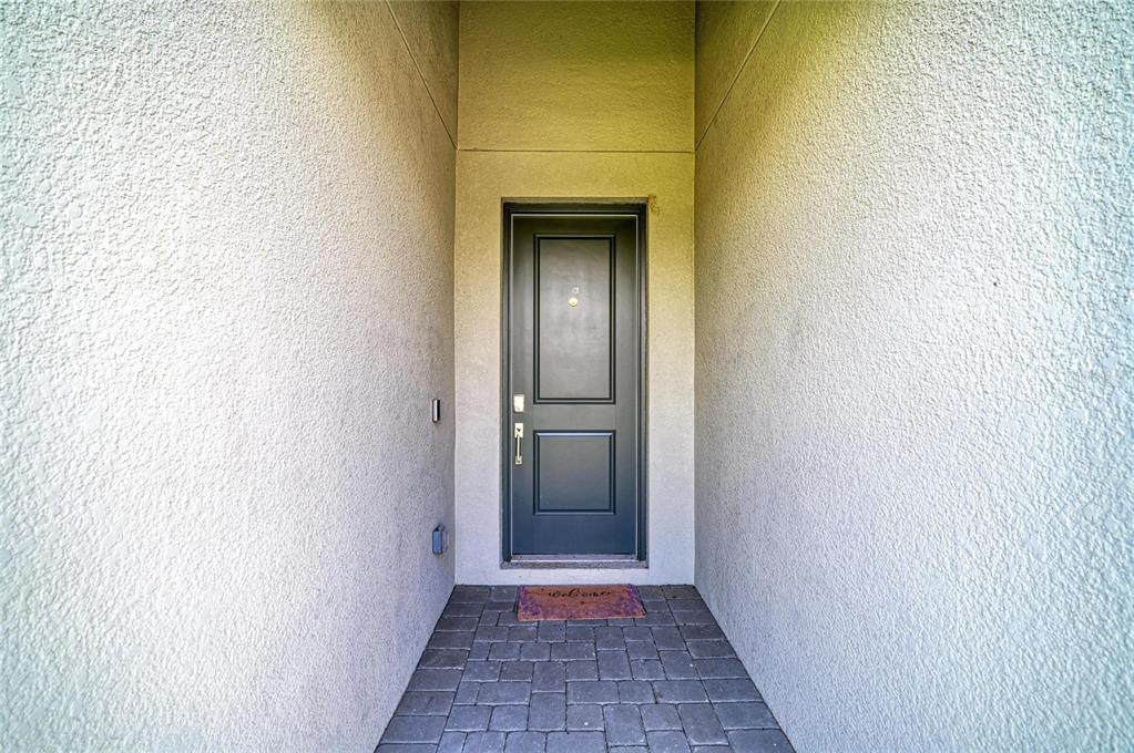 A dark gray front door is set within a recessed entryway with textured stucco walls — 15045 SERENE SHORES LOOP, BRADENTON, FL