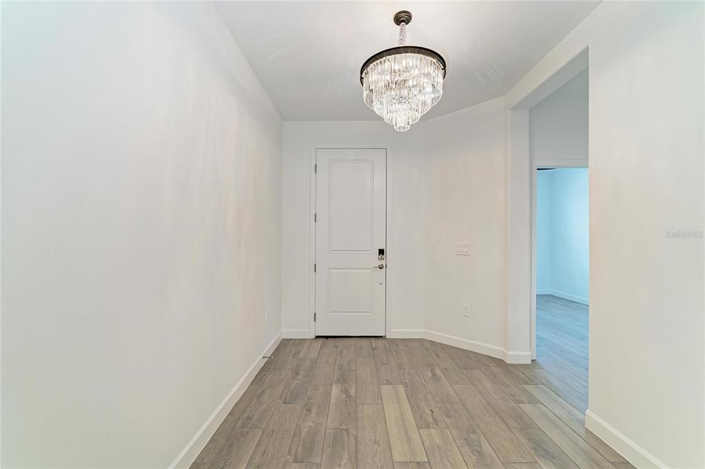 A bright entryway features a crystal chandelier, white walls, and wood-look tile flooring — 15045 SERENE SHORES LOOP, BRADENTON, FL