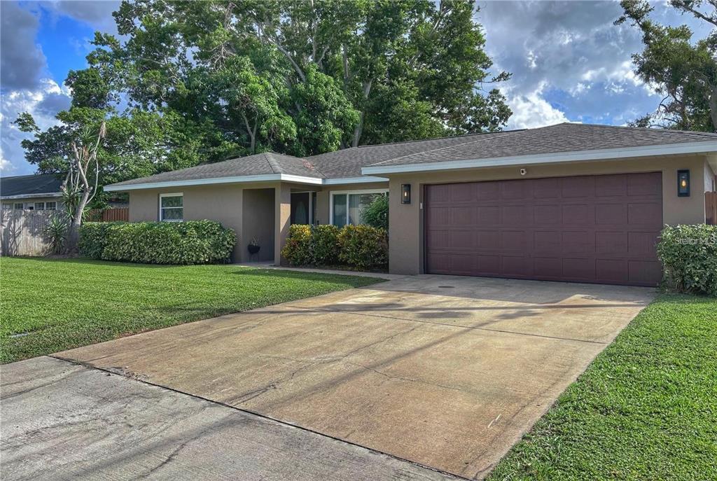 A single-story house with a brown garage door, concrete driveway, and green landscaping — 4033 13TH AVENUE W, BRADENTON, FL