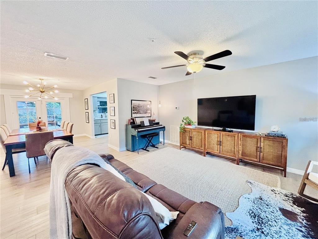 A living room features a brown leather sofa, a television on a wooden console, and piano — 4033 13TH AVENUE W, BRADENTON, FL