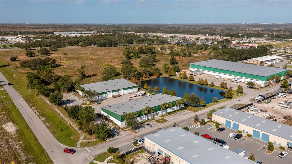 An aerial view shows several industrial warehouse buildings situated near a retention pond and road — 1770 BUSINESS CENTER LANE, KISSIMMEE, FL