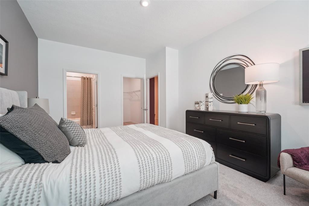 A bedroom features a bed with a patterned duvet, a dark dresser, and a mirror — 23603 GRINDSTONE WAY, SORRENTO, FL