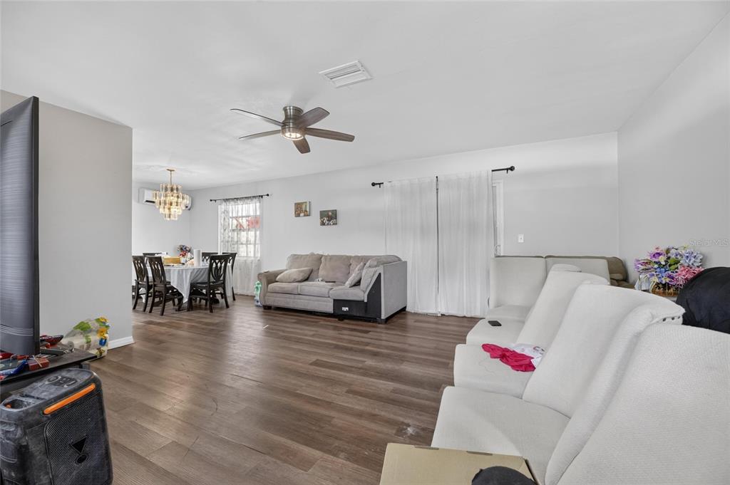 A living room with wood-look flooring, a ceiling fan, and an adjacent dining area — 202 9TH STREET NE, RUSKIN, FL