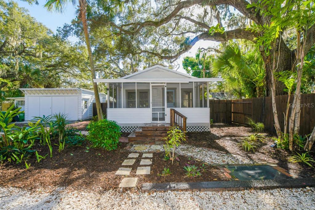 A white cottage with a screened-in front porch sits behind a gravel path and landscaping — 1230 35TH STREET, SARASOTA, FL